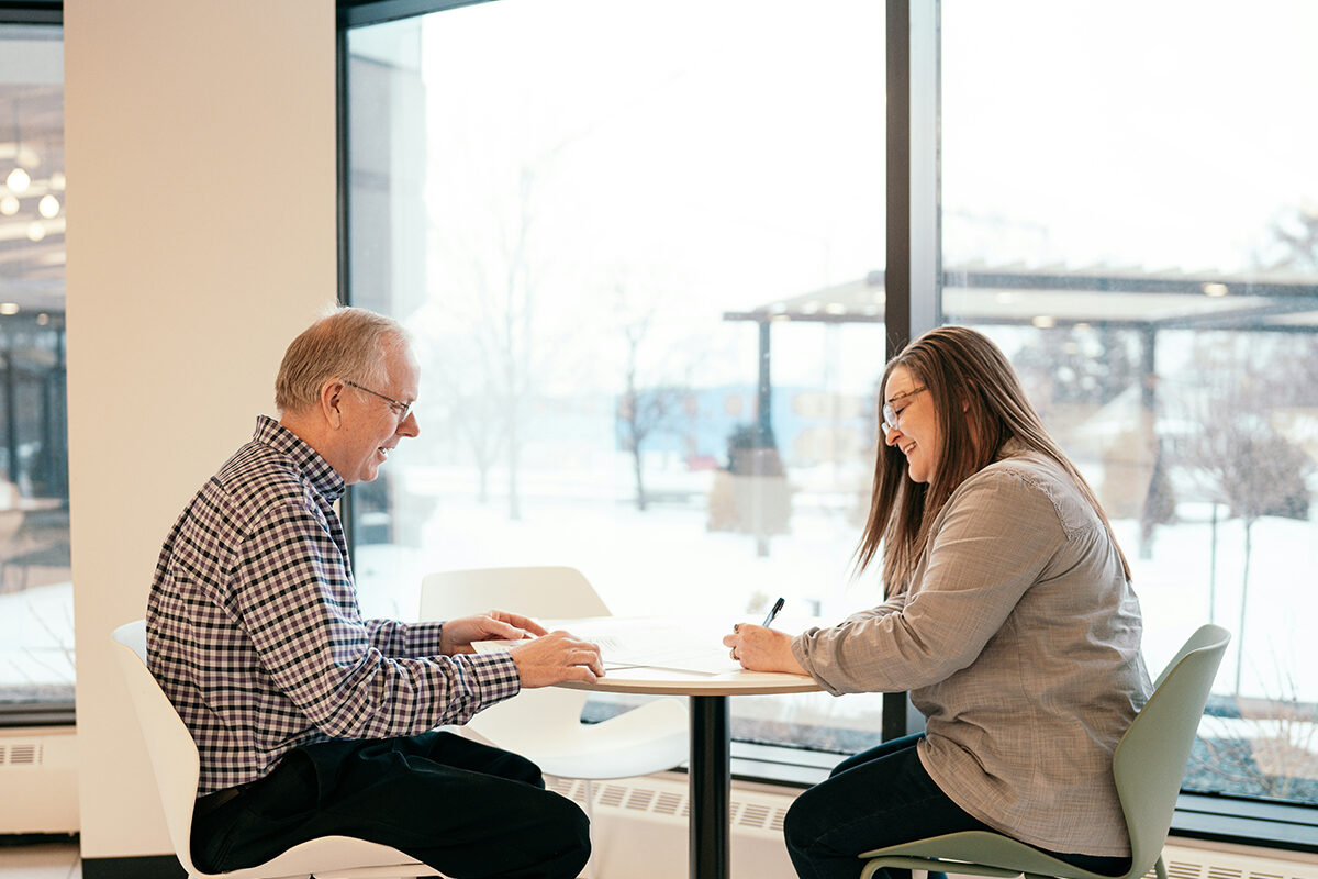 A man and woman sitting at a small table having a meeting