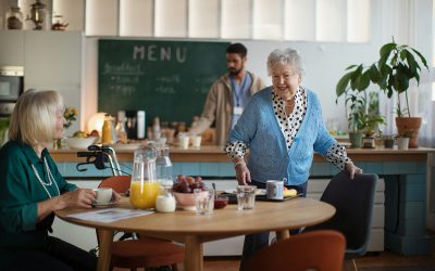 Two older ladies at a table in a cafe setting, with food and drink items on the table