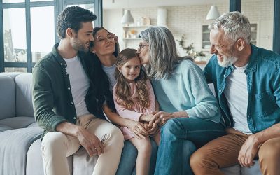 A family of five people sat on a sofa depicting parents and grandparents with a child