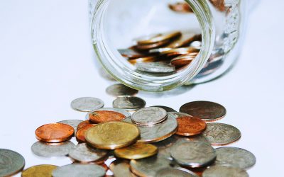 Jar knocked over with coins spilling out on table