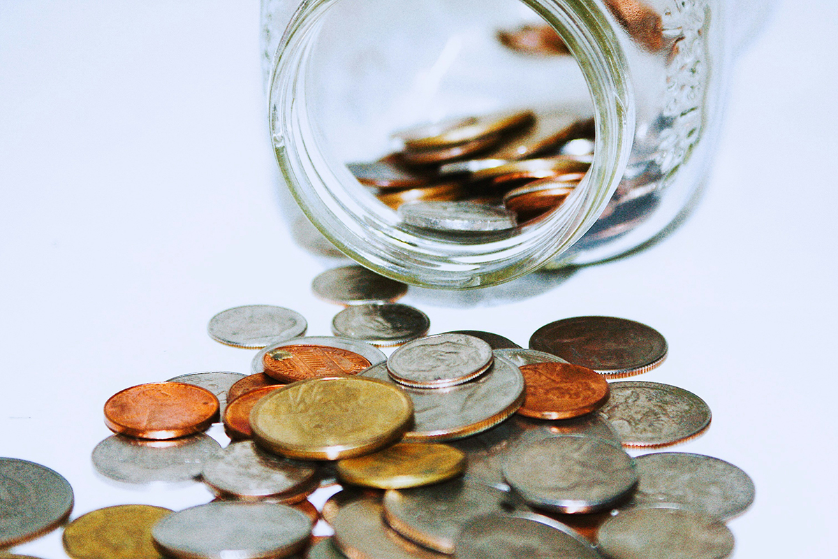 Jar knocked over with coins spilling out on table