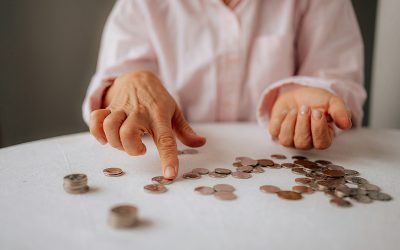 Coins spread out on a table with a person moving coins to count them