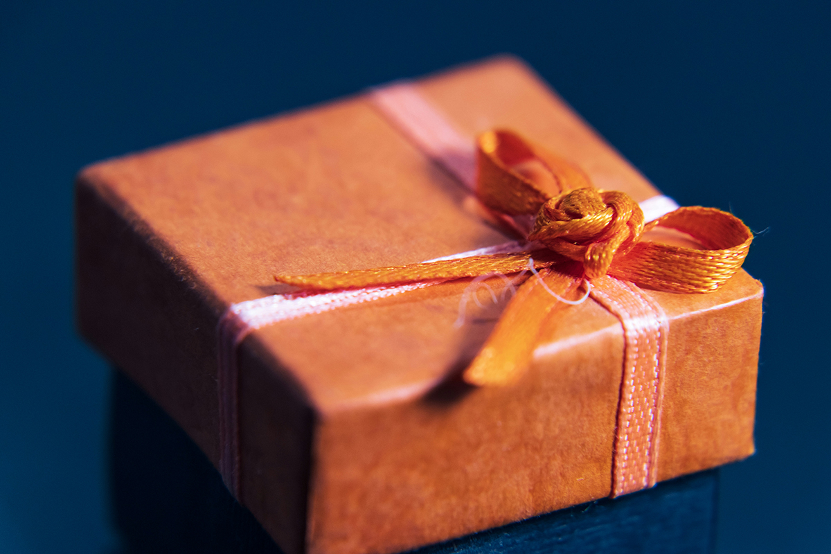 An orange square neatly wrapped present with a bow on a navy background