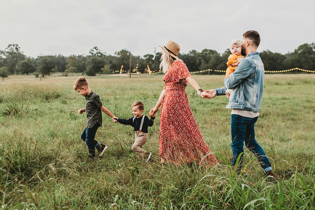 A family of five walking in a field holding hands