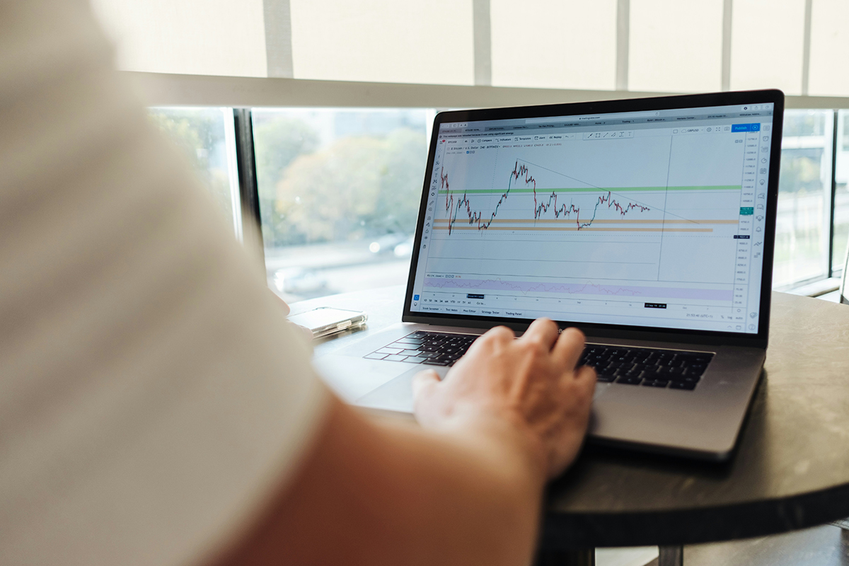 A person sat at a laptop with stock market data on the screen